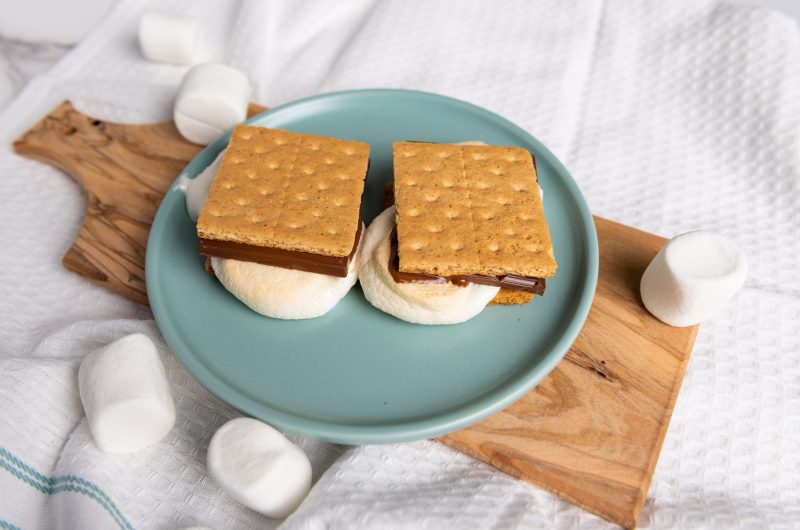 air fryer smores on a teal plate sitting on a cutting board