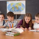 Four classroom children sitting at a table doing work