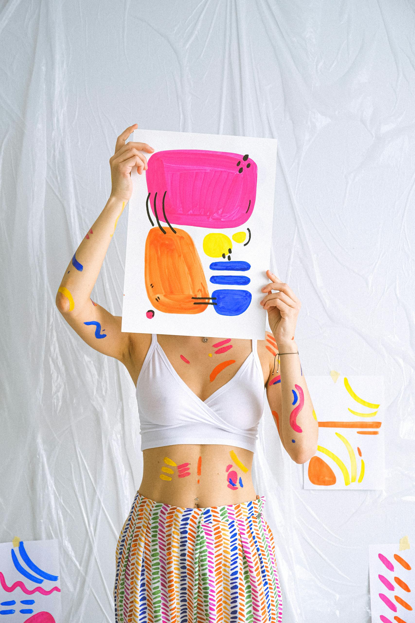 Bright abstract art piece held by decorated woman, embracing creativity.