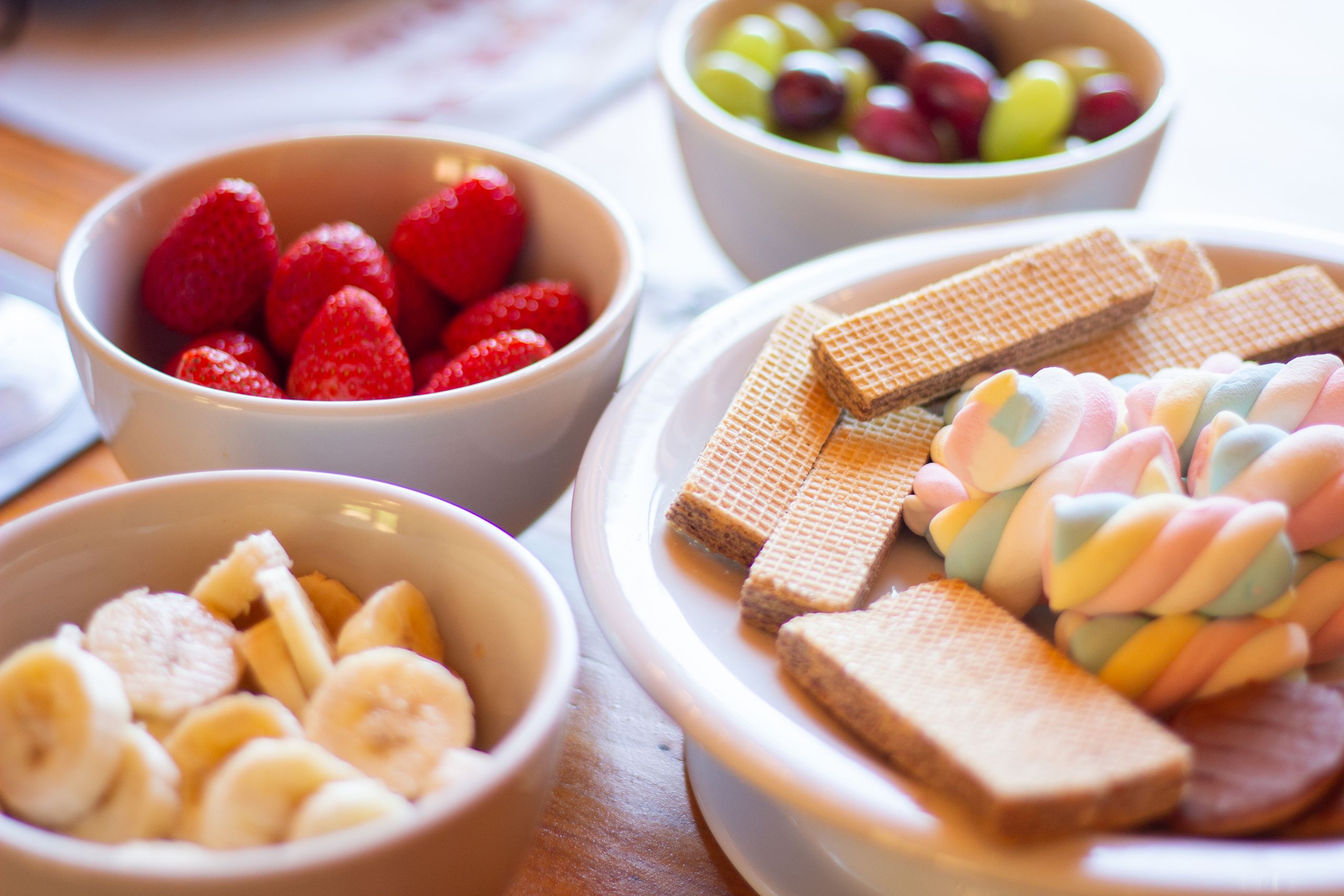 Colorful display of fruits and sweets including strawberries, bananas, grapes, wafers, and marshmallows.